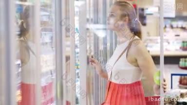 在超市的冷冻区购买乳制品或冷藏食品的年轻妇女打开冰箱门